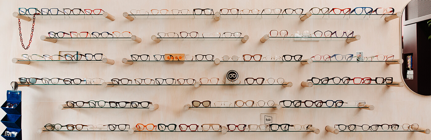 The wall of Peep Optical in Yarraville lined with glass shelves full of glasses and sunglasses.