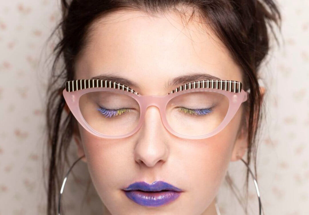 Close up of a woman with purple lipstick with fun, oversized glasses frames by Onirico eyewear.