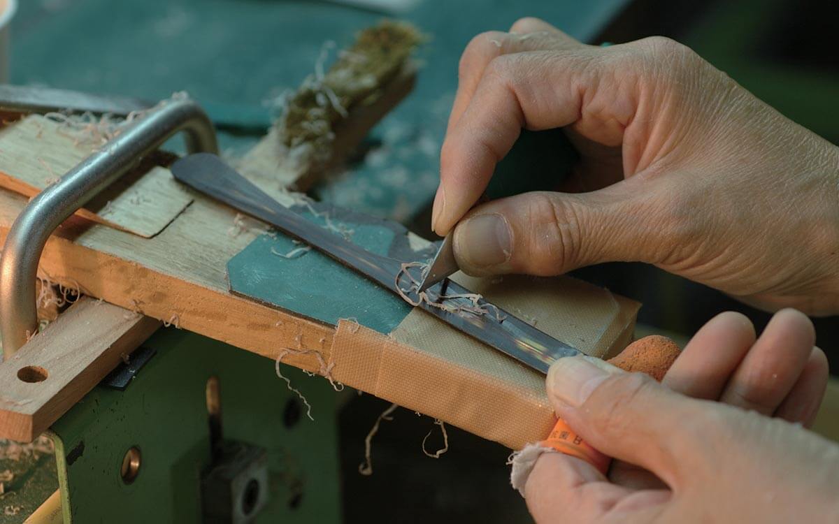 Masunaga glasses being hand made during the refined manufacturing process, with a man holding the tools over a workbench.