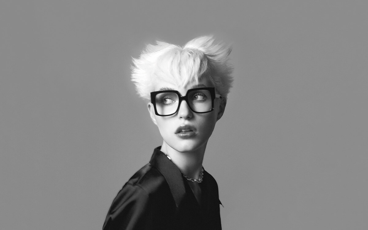 Black and white fashion photo of a model with blonde hair wearing vintage style designer JPLUIS eyewear.