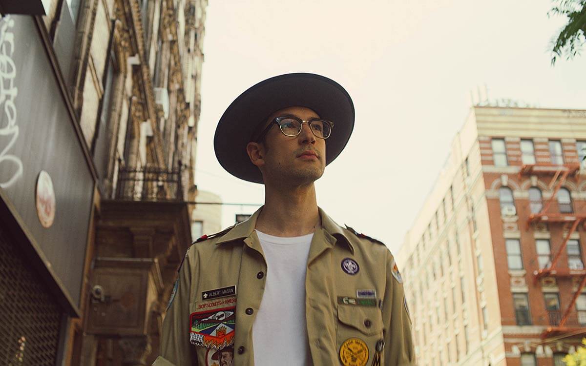 A man wearing glasses from Moscot melbourne, with a fashionable hat and shirt.