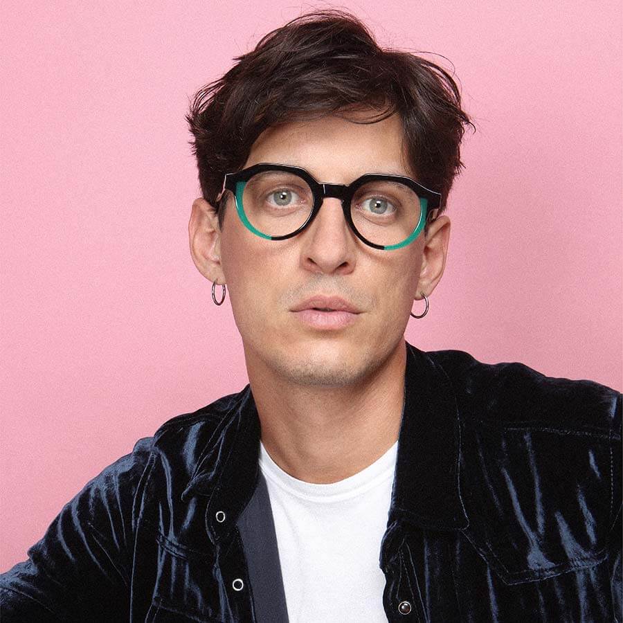 A male model wearing a pair of hand-made glasses made by Onirico eyewear with bold colours and thick frames.