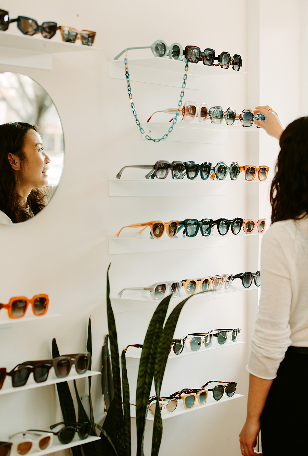 Alison Wong, owner at Peep Optical, selecting eyewear from a shelf in her store.