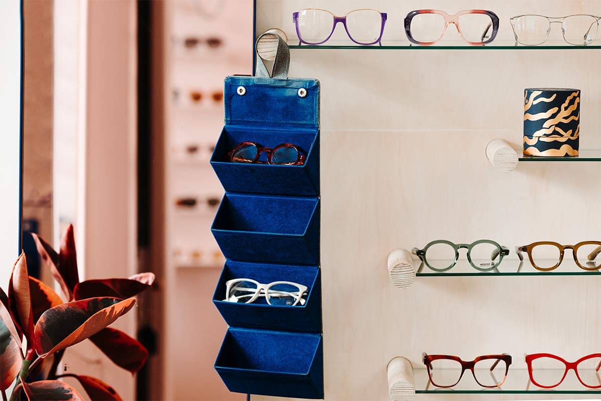 Beautiful glasses displayed in the Peep Optical store, on glass shelves and in a blue hanging holder.