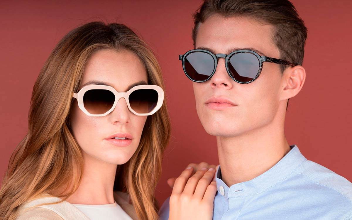 A couple both wearing sunglasses by Res Rei eyewear, with bold white and black frames.