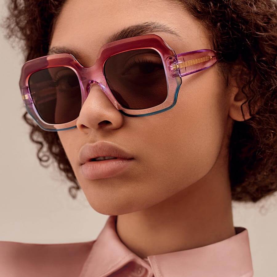A female model wearing ultra-feminine glasses by Res Rei eyewear with pink gradient frames.